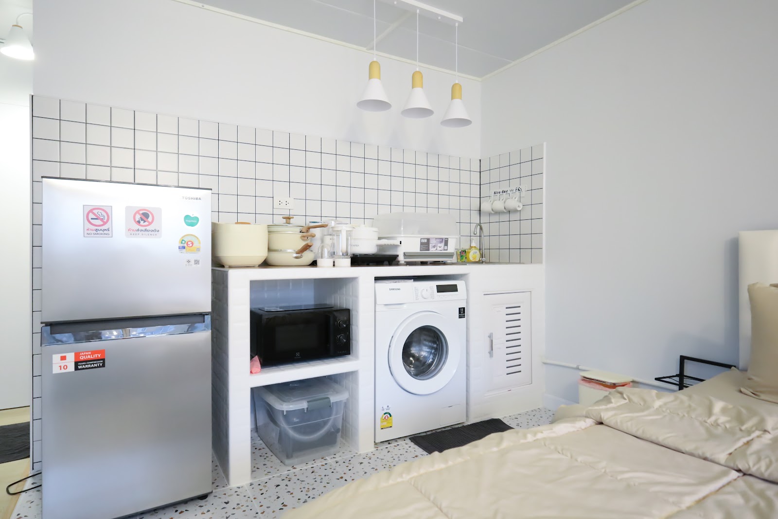 White-tiled kitchen with washer and pendant lights